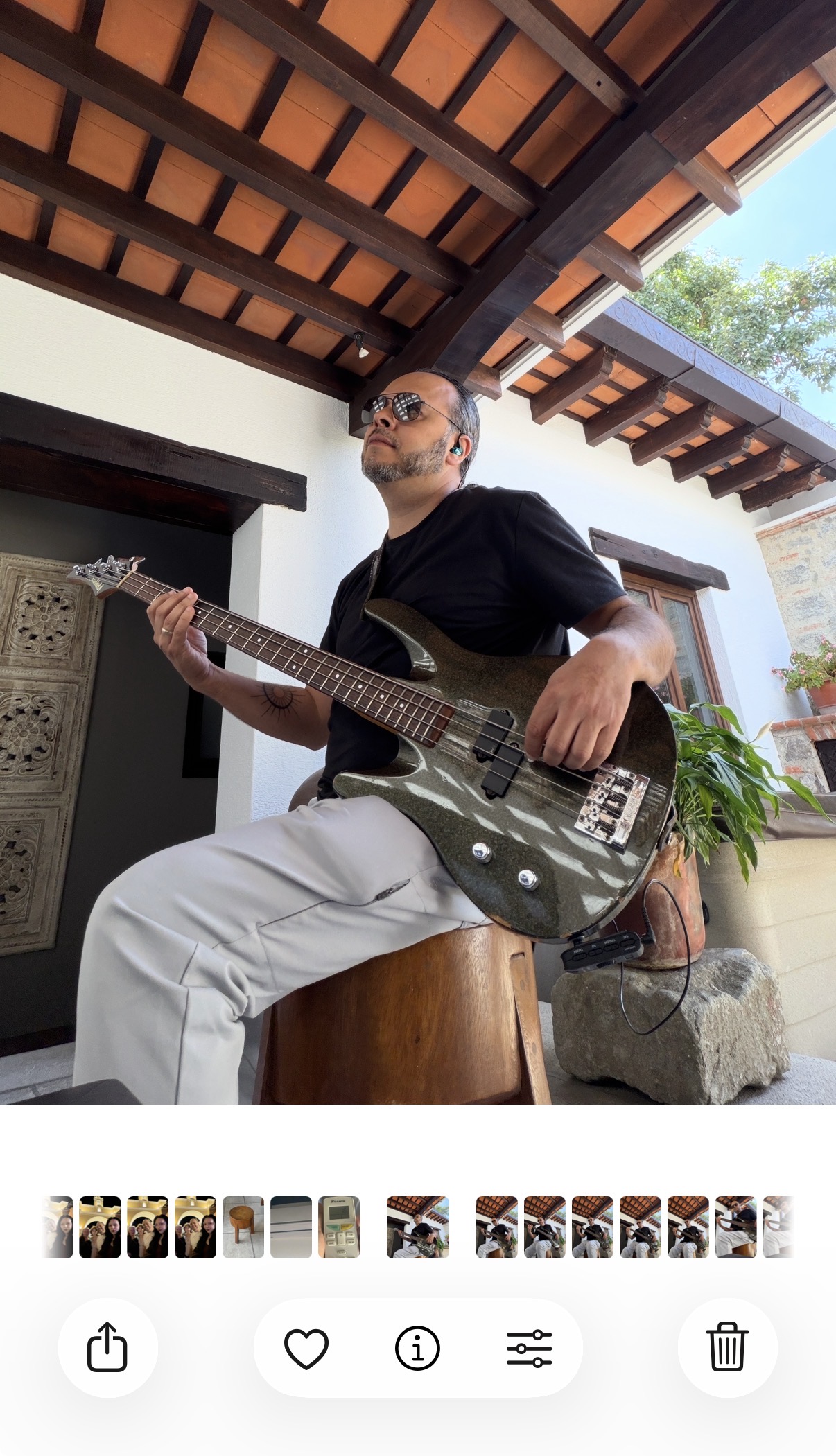 Giovanni Meza sentado en el patio tocando el bajo